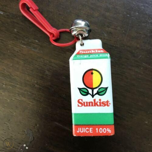 a plastic bell charm resembling a miniature Sunkist orange juice